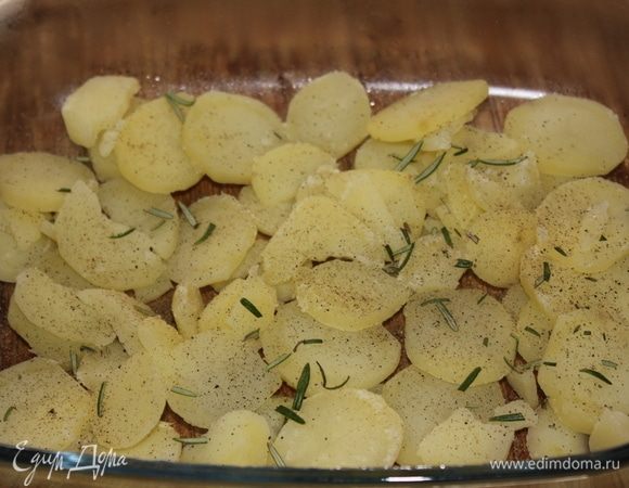В стеклянную огнеупорную посуду выложить отваренный картофель, распределить по всей поверхности дня посуды. Посыпать молотым черным перцем, измельченными листиками свежего розмарина.