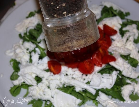 Помидоры черри выложить на слой моцареллы в центр, посыпать свежемолотым черным перцем, посолить.