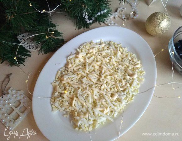 У нас 5 вареных яиц. Из них берем 5 желтков и 2 белка, трем на крупную терку, выкладываем на тарелку. Делаем сеточку из майонеза. Я использовала майонез ТМ «МахеевЪ» с перепелиным яйцом. Это наш первый слой.
