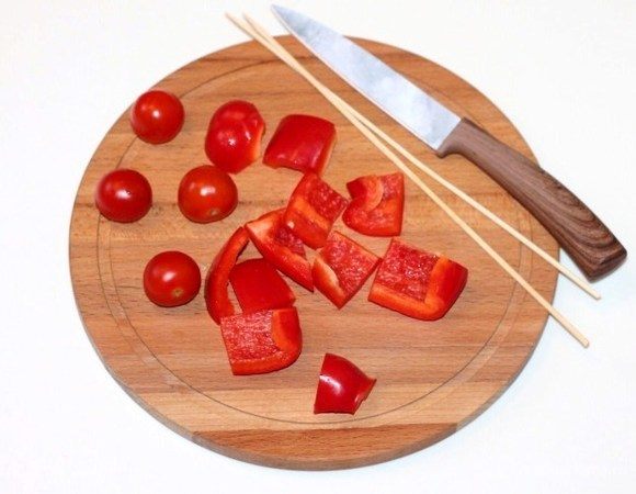 Помидоры черри порезать половинками. Сладкий перец очистить от семян и порезать кусочками.
