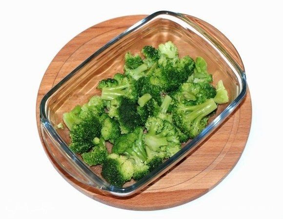 Капусту брокколи выложить в кипящую воду, 1-2 минуты бланшировать и выложить в сито. Форму для запекания смазать растительным маслом и выложить капусту.