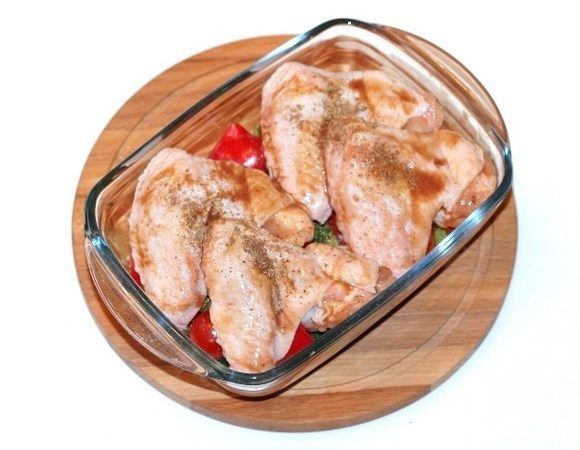 Сверху овощей выложить куриные крылышки и посыпать приправой для курицы 0,5 ч.л., посолить и поперчить. Накрываем формочку для запекания фольгой и отправляем в духовку на 40 минут или до готовности. 
