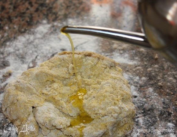 Выложить тесто на рабочую поверхность, присыпанную мукой, добавить 1 ст. ложку оливкового масла Extra Virgin.