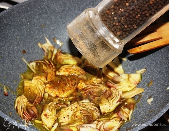 Выложить артишоки в разогретое ароматное масло на сковороду, поперчить, и на слабом огне при закрытой крышке, томить в течение 8- 10 минут, периодически помешивая.