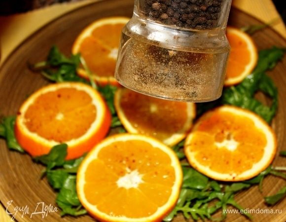 Нарезать апельсин кружочками, выложить поверх слоя руколы, поперчить, посолить.