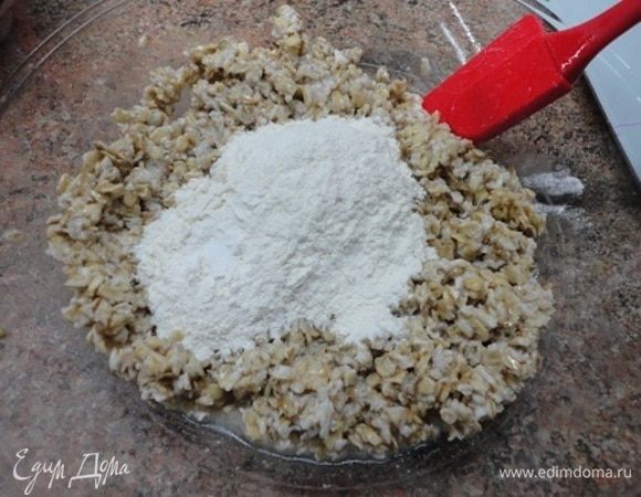 К хлопьям добавить растительное масло. Корицу и разрыхлитель смешать с мукой и добавить к хлопьям. Перемешать.