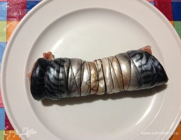 Теперь сворачиваем плотно рыбу от хвоста в направление к отрезанной голове.
И тут же обматываем приготовленными заранее нитками, как на фото. Если вам трудно сворачить рыбу и обматываеть ее одновременно, то попросите кого-то из домашних пусть вам помогут. Я поначалу просила помощи, теперь так наловчилась, делаю такую скумбрию часто.