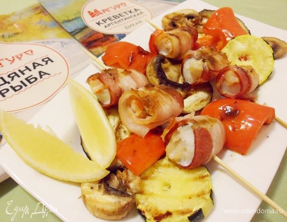 Выложить на тарелку овощи-гриль, рыбу с креветками в беконе. Подавать с дольками лимона.