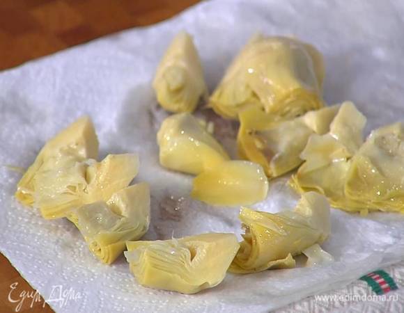 Артишоки выложить на бумажное полотенце, чтобы удалить излишки масла, затем разрезать на 4 части.