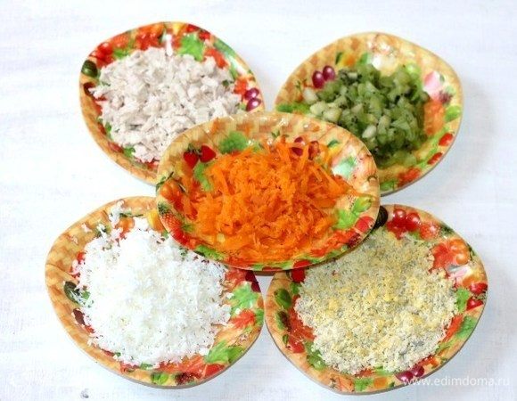 Подготовим продукты для салата. Отвариваем куриное филе с добавлением соли, лаврового листа и перца горошком. Куриное филе охлаждаем и мелко нарезаем.
Яйца и морковь отварить, охладить и очистить. Яйца разделить на белки и желтки. Морковь и яичный белок натереть отдельно на средней терке. Желток растереть вилкой. 
Киви очистить и нарезать маленькими кубиками.