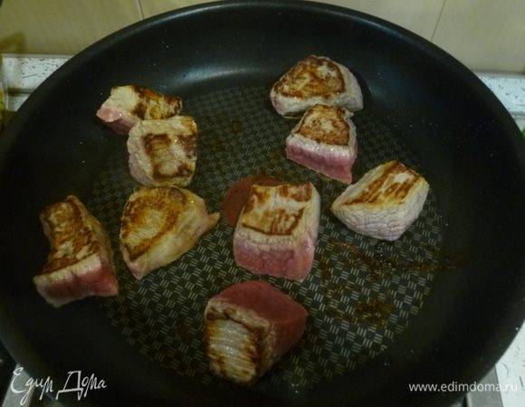 Говядину нарезать кубиками со стороной 3-4 см. В той же сковороде обжарить говядину порциями до румяной корочки. Переложить к луку.