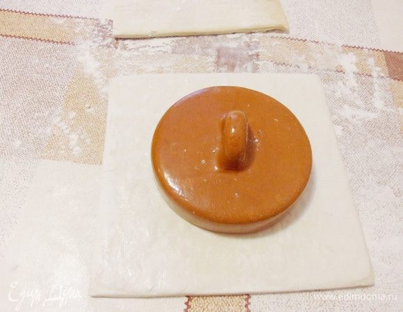 На подпыленный мукой стол выложить размороженные квадраты слоеного теста. 