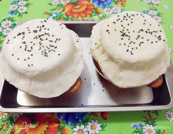 Накрыть тестом горшочки, прижать тесто к стенкам. Сверху крышечки из теста посыпать семенами кунжута. Отправить горшочки со щами в разогретую до 200°С духовку. Запекать до готовности теста (около 15 минут).