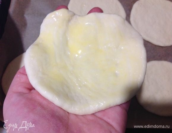 Теперь каждый колобок раскатываем в лепешку среднего размера, как на фото, слишком тонко не раскатывайте!
Подготовили сразу 2 противня, застилаем оба пергаментными листами бумаги.
Растопили сливочное масло, дали остыть до теплого состояния.
Теперь смазываем с помощью силиконовой кисточки одну часть лепешки (это будет нижняя часть) и кладем этой смазанной стороной вниз на пергаментный лист, и так все лепешки.
