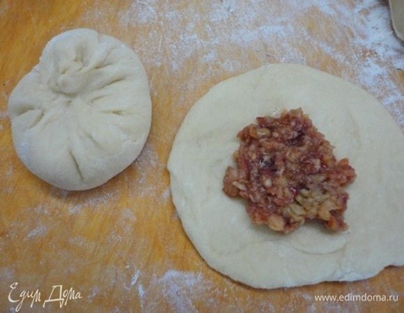 Тесто разделить на шарики весом 90–100 г, раскатать их в лепешки, в центр выложить по десертной ложке начинки и защипать края к центру.