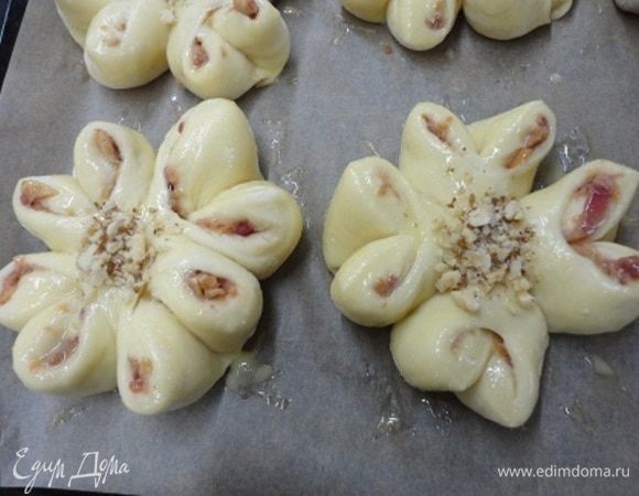 Выложить на противень, дать расстояться, смазать яйцом и в серединку каждого цветка насыпать орехи или мак.