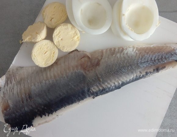 Яйца отварить, очистить от скорлупы, отделить желтки от белков. Сельдь разобрать на филе. Нам потребуется 2 филе сельди.