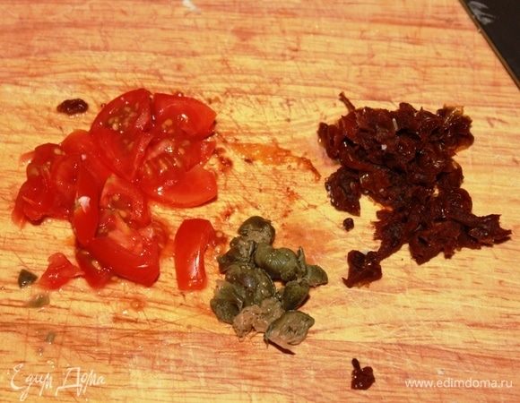Тем временем нарезать 2 помидора черри, измельчить каперсы (если они у вас хранятся под солью, промойте их немного под проточной водой, чтобы не переборщить с солью), нарезать 1 вяленый томат.