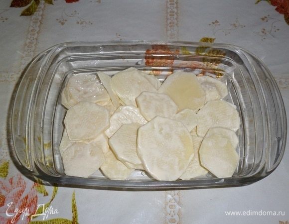 В глубокую форму для запекания выкладываем половину картофеля с майонезом. Равномерно распределяем в форме.