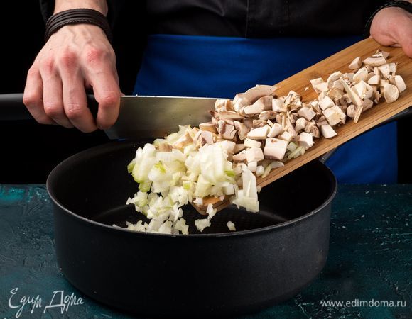 Нарежьте мелким кубиком шампиньоны. Нарежьте лук и обжарьте в растительном масле до легкой румяной корочки.