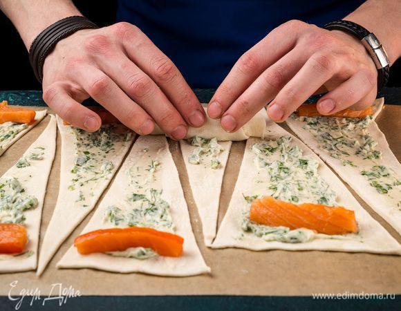 Сверху положите ломтики красной рыбы. Сверните рулетики и слегка загните края.
