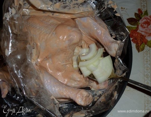 Через 1 час курицу кладем в пакет для запекания. Внутрь тушки кладем нарезанный лук и 2 ст. л. маринада.