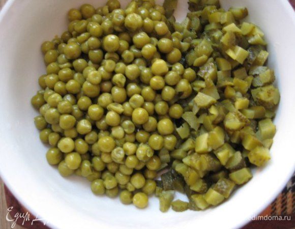 Огурцы нарезать мелким кубиком, слить с зеленого горошка рассол. Добавить в салат.