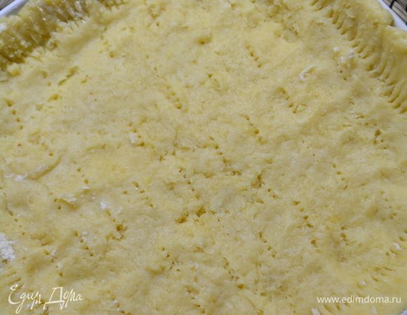 Тесто достать из холодильника, выложить в форму (диаметр 26 см) и разровнять, сделать бортики, наколоть всю поверхность вилкой. Сверху на тесто уложить пекарскую бумагу и высыпать горох или фасоль. Выпекать при 200°С, 10 минут.