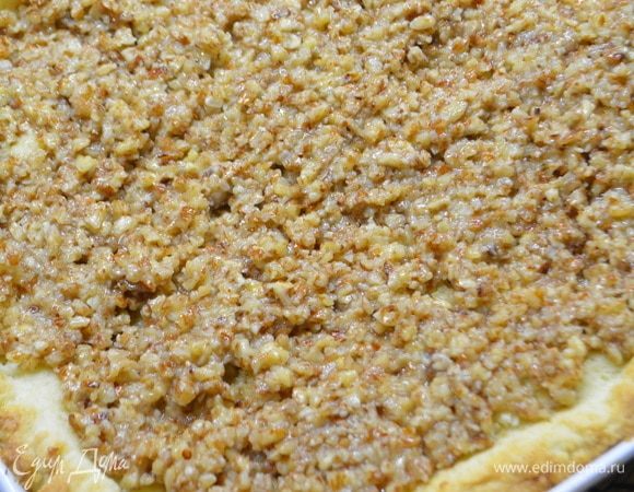 Достать подрумяненное тесто, удалить бумагу с фасолью и выложить на тесто ореховую начинку.