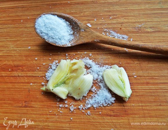 Раздавить чеснок с крупной солью.