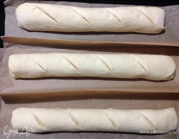 Теперь все закрученные багеты складываем в формы из пергамента.
Присыпаем багеты через ситечко мукой (можете смазать желтком и присыпать кунжутом) и делаем надрезы острым ножом и резким движением, если делать медленно да еще и тупым ножом, то тесто будет просто тянуться за ножом. 
