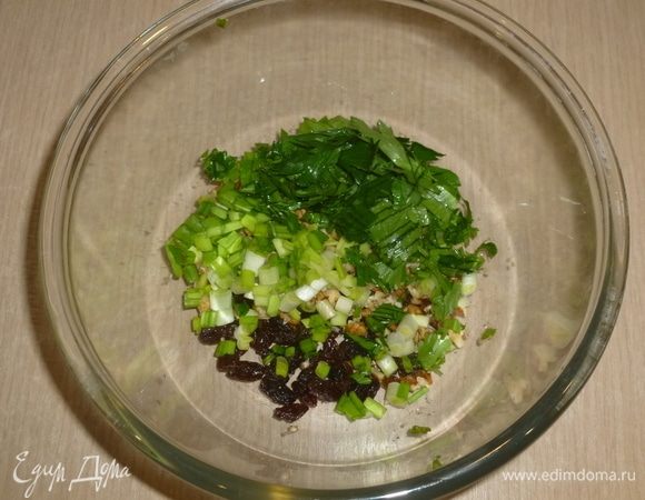 Зелень нарезать. Соединить в большой миске изюм, орехи и зелень.