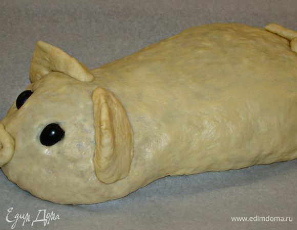 Раскатать в овал вторую часть теста и намотав на скалку, аккуратно накрыть кулебяку. Края теста подвернуть под брюшко. Из оставленного небольшого кусочка теста сформировать ушки и хвостик. 