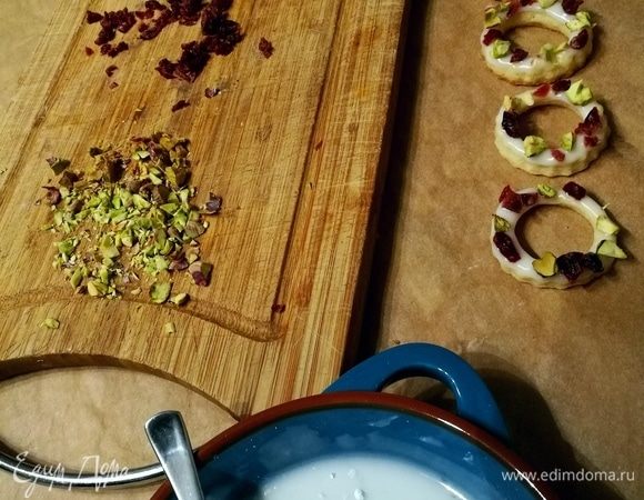 Теперь можно заняться творчеством и украшательством. Из лимонного сока и сахарной пудры смешать помадку. Нарубить фисташки и вяленую или сушеную вишню или клюкву. Колечки обмакнуть в помадку и посыпать орешками и фруктами. Дать подсохнуть. 