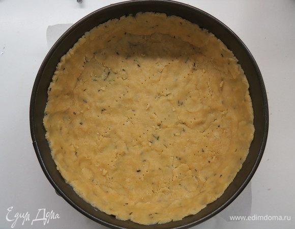 Быстро замесить тесто до гладкого состояния, завернуть его в пищевую пленку и убрать в холодильник на 30 минут.
На дно формы диаметром 22 см выложить пекарскую бумагу, спустя отведенное время раскатать тесто и выложить в форму, сформировать бортики.
Тесто наколоть вилкой, поставить в морозилку минут на 10. Тем временем разогреть духовку до 180°С. Выпекаем подмороженную основу в течение 15 минут, затем достаем и отставляем в сторону.