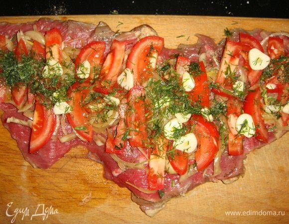 У меня два куска мяса, поэтому все ингредиенты я разделила на две части. На мясо выложить лук из маринада, помидоры, чеснок и посыпать мелко нарезанным укропом или петрушкой.