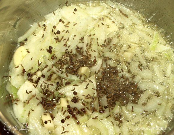 В кастрюле с толстым дном разогреть сливочное и растительное масло. Обжарить в нем чеснок и лук до золотистого цвета. Добавить пряности к луку с чесноком. Обжарить две минуты.