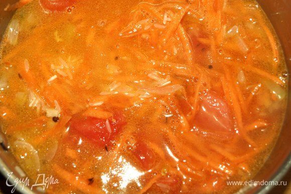 Добавить помидоры, морковь, рис и горячую воду (заранее нагреть). Довести до кипения. Накрыть крышкой и убавить огонь. Варить на медленном огне 15 минут.