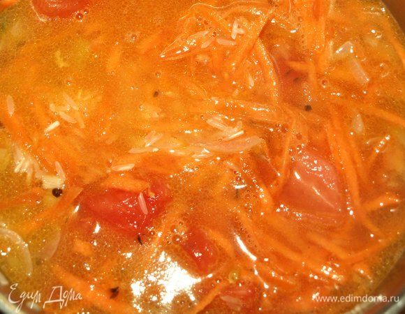 Добавить помидоры, морковь, рис и горячую воду (заранее нагреть). Довести до кипения. Накрыть крышкой и убавить огонь. Варить на медленном огне 15 минут.