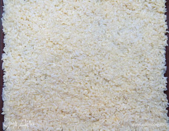 Рисовую массу выкладываем на противень, застеленный бумагой для выпечки или силиконовым ковриком. Бумагу или коврик предварительно немного смазать растительным маслом. Равномерно распределяем рисовую массу. Толщина слоя составляет примерно 5–7 мм.