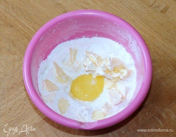 Сделать углубление в центре и добавить яичный желток, охлажденное и мелко порезанное сливочное масло и 2 ст. л. холодной воды. Смешать все ингредиенты и замесить тесто до однородной, гладкой консистенции.
