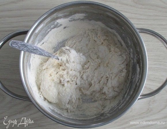 Добавьте в опару остальную муку и замесите тесто сначала ложкой, а затем смазанными маслом руками.