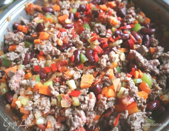 Затем добавить фарш в общую сковородку (кастрюлю) с овощами.
Закрыть крышкой, дождаться, пока чили кон карне закипит. Уменьшить огонь до минимального и оставить томиться  примерно на 1 час, периодически помешивая. 
За 10-15 минут до окончания приготовления добавить фасоль. Из банки с фасолью предварительно нужно слить жидкость. Затем добавить бальзамический уксус. Еще раз посолить, поперчить по вкусу и аккуратно, чтобы не повредить фасоль, фасолины должны остаться целыми, перемешать. 