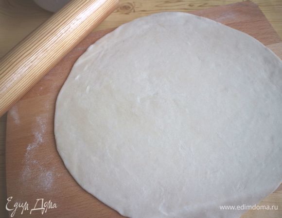 Разделить каждый шар на 2 равные части теста, руками придать форму лепешек, раскатать каждую из них на рабочей поверхности присыпанной мукой.
