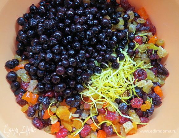 Сухофрукты промыть, обсушить. Натереть цедру с одного лимона и одного апельсина. Черную смородину предварительно разморозить, дать лишней воде стечь. Сложить все ингредиенты в глубокую большую миску, приправить соком от одного лимона.