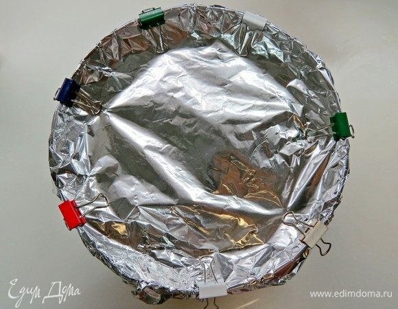 Сверху плотно оборачиваем миску фольгой, она защитит наш пудинг от лишней влажности и предотвратит испарение алкоголя. Я для удобства закрепила скрепками-крокодильчиками.
Затем организуем водяную баню. Для этого можно поместить миску в кастрюлю бОльшего объема, но так чтобы маленькая миска не касалась дна кастрюли. Мне было проще использовать мультиварку, я поставила миску на решетку для пароварки и готовила пудинг в режиме «Варка на пару», не забывая каждые 40 минут подливать воду! Крышка мультиварки у меня естественно не закрывалась, я просто накрыла всю свою конструкцию непромокаемой детской клеенкой. Получилась такая мини-баня.
Таким образом, готовим пудинг на водяной бане 3-4 часа.
Честно скажу, что это самая трудоемкая часть приготовления пудинга, так как все время надо следить за уровнем воды, в общем не расслабишься. :)