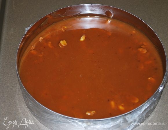 Кольцо диаметром 20 см затягиваем пленкой. Первый слой — бисквит с орехом и слой жидкой карамели. Убираем все в морозильную камеру для застывания карамели.