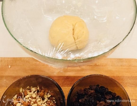 Получившийся шарик теста хорошо обмять, смазать маслом и убрать под пленку (или накрыть мокрым полотенцем) на 30 минут (у меня простоял около часа). Замочить изюм в кипятке, миндаль измельчить, но не в муку, чтобы чувствовались кусочки. 