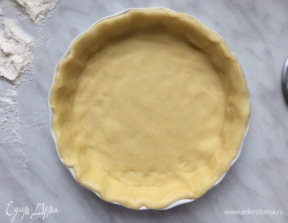 Достаньте один диск теста из холодильника, выложите на рабочую поверхность и раскатайте в тонкий пласт. Распределите тесто по дну и стенкам формы для выпечке и уберите в холодильник, пока вы готовите начинку.