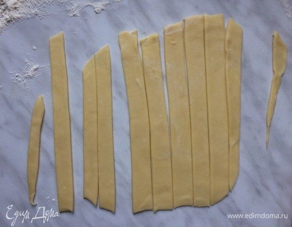 Достаньте из холодильника второй диск теста, выложите на рабочую поверхность и раскатайте в тонкий пласт. При помощи ножа или фигурного резака нарежьте тесто на полоски.